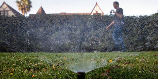 In this Friday, June 5, 2015, photo, Tony Corcoran records sprinklers watering the lawn in front of a house in Beverly Hills,