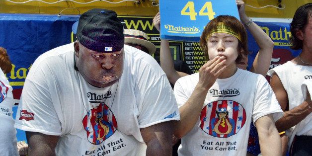 NEW YORK - JULY 4: Eric 'Badlands' Booker (L) of New York and Takeru Kobayashi of Japan stuff hot dogs in their mouths at the end of the annual hot dog eating contest at Coney Island July 4, 2003 in New York City. Kobayashi, who set a world record of 50 1/2 hot dogs in last year's contest, downed 44 to easily win again this year. (Photo by Chris Hondros/Getty Images)
