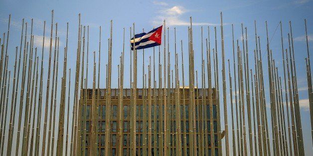 A Cuban flag flutters next to the US Interests section in Havana, on July 2, 2015. Private business shops --visa-related tasks, coffee shops and lockers for mobile phones and handbags-- flourish around the US Interests section. AFP PHOTO/YAMIL LAGE (Photo credit should read YAMIL LAGE/AFP/Getty Images)
