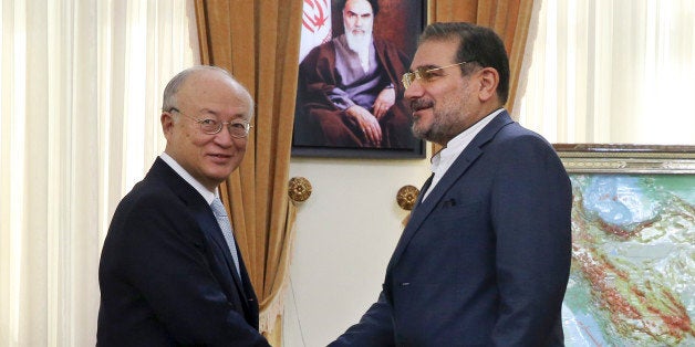 Secretary of Iran's Supreme National Security Council Ali Shamkhani, right, welcomes Director General of the International Atomic Energy Agency (IAEA) Yukiya Amano, at the start of their meeting in Tehran, Iran, Thursday, July 2, 2015. Iran has met a key commitment under a preliminary nuclear deal setting up the current talks on a final agreement, leaving it with several tons less of the material it could use to make weapons, according to a U.N. report issued Wednesday. A portrait of the late Iranian revolutionary founder Ayatollah Khomeini hangs on the wall at rear. (AP Photo/Vahid Salemi)