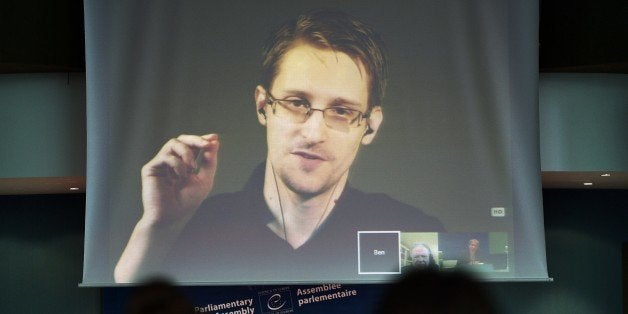 NSA former intelligence contractor Edward Snowden talks as he participates via video link from Russia (Above) to a parliamentary hearing on the subject of 'Improving the protection of whistleblowers', held by Dutch rapporteur Pieter Omtzigt (Bottom C) on June 23, 2015, at the Council of Europe in Strasbourg, northeastern France. Snowden, who has been granted asylum in Russia, is being sought by Washington which has branded him a hacker and a traitor who endangered lives by revealing the extent of the NSA spying program. AFP PHOTO / FREDERICK FLORIN (Photo credit should read FREDERICK FLORIN/AFP/Getty Images)