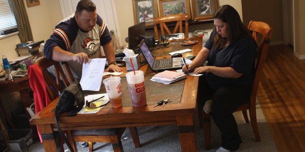 LAKEWOOD, CO - OCTOBER 07: Iraq War veteran Brad Hammond (L) helps as his wife Dani Hammond writes checks to pay household bills on October 7, 2011 at their house in Lakewood, Colorado. Seven years after returning home from a year-long deployment in Tal Afar, Iraq, Hammond continues to experience severe post traumatic stress disorder (PTSD), and the effects of traumatic brain injuries he sustained in combat. His condition has made it impossible for him to hold a fulltime job and the family is on a tight budget. He helps his wife Dani care for their three children, while also taking private mentoring classes to help improve his attention and cognitive skills. Hammond was on a team of U.S. soldiers who opened fire on a carload of Iraqi civilians on January 18, 2005 in Tal Afar, Iraq, killing two, when they did not stop at a checkpoint. (Photo by John Moore/Getty Images)