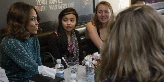 US first Lady Michelle Obama(L) talks with youths during a luncheon round table at We the Pizza/Good Stuff Eatery on November 20, 2014 in Washington, DC. US President Barack Obama and US first Lady Michelle Obama met with youth from the Standing Rock Sioux Tribe in North Dakota. AFP PHOTO/Brendan SMIALOWSKI (Photo credit should read BRENDAN SMIALOWSKI/AFP/Getty Images)