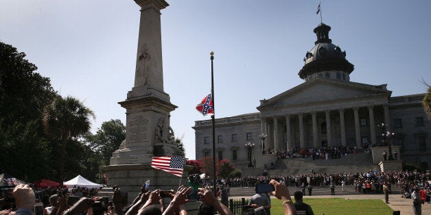 COLUMBIA, SC - JULY 10: A crowd cheers as a South Carolina state police honor guard lowers the Confederate flag from the Statehouse grounds on July 10, 2015 in Columbia, South Carolina. Republican Governor Nikki Haley presided over the event after signing the historic legislation the day before. (Photo by John Moore/Getty Images)