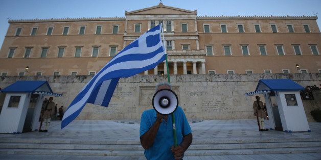 ATHENS, GREECE - JULY 09: A man waves a Greek flag and uses a megaphone in front of the Greek parlaiment during a pro-european rally on July 9, 2015 in Athens, Greece. The Greek government has only hours left to offer Eurozone creditors a viable plan to recovery. Greece's creditors will review the measures before European leaders meet on Sunday to decide on the country's fate and whether it should stay in the euro. (Photo by Christopher Furlong/Getty Images)
