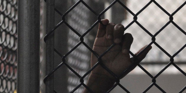 GUANTANAMO BAY NAVAL BASE, CUBA - APRIL 27: (EDITORS NOTE: Image has been reviewed by the U.S. Military prior to transmission) A Guantanamo detainee holds onto a fence inside the Camp 6 high-security detention facility April 27, 2010 at Guantanamo Bay U.S. Naval Base, Cuba. Today, a military tribunal began hearings on whether Omar Khadr, a Candian by birth who was 15 at the time of his capture in Afghanistan, made statements to interrogators under duress, which would render them them inadmissable in the first military tribunal to be held under the Obama Administration. (Photo by Michelle Shephard-Pool/Getty Images)