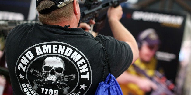 HOUSTON, TX - MAY 05: An attendee wears a 2nd amendment shirt while inspecting an assault rifle during the 2013 NRA Annual M