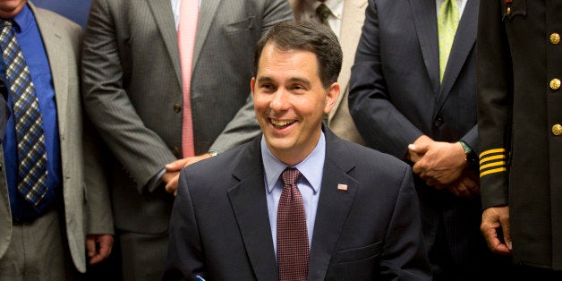 Wisconsin Gov. Scott Walker signs a gun bill at the Milwaukee County Sheriff's office that eliminates a 48-hour waiting period for handgun purchases. Wednesday, June. 24, 2015, in Milwaukee. (AP Photo/Jeffrey Phelps