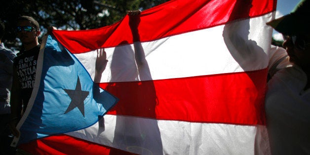 People march holding a Puerto Rican national flag in San Juan, Puerto Rico, Saturday, Nov. 23, 2013. Puerto Ricans marched through the island's capital to demand the release of Oscar Lopez, a 70-year-old Puerto Rican nationalist who belonged to a militant group that sought independence for the U.S. territory decades ago. Lopez is scheduled to be released from a federal prison in Indiana in June 2023. He was sentenced to 55 years in prison after a 1981 conviction on charges including seditious conspiracy, use of force to commit robbery and interstate transportation of firearms. (AP Photo/Ricardo Arduengo)