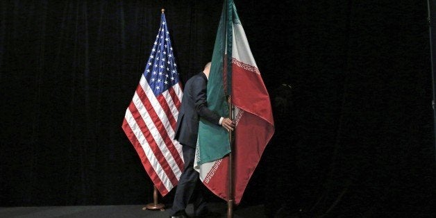 A staff removes the Iranian flag from the stage after a group picture with foreign ministers and representatives of Unites States, Iran, China, Russia, Britain, Germany, France and the European Union during the Iran nuclear talks at the Vienna International Center in Vienna on July 14, 2015. Iran and six major world powers reached a nuclear deal on Tuesday, capping more than a decade of on-off negotiations with an agreement that could potentially transform the Middle East, and which Israel called an 'historic surrender'. AFP PHOTO / POOL / CARLOS BARRIA (Photo credit should read CARLOS BARRIA/AFP/Getty Images)