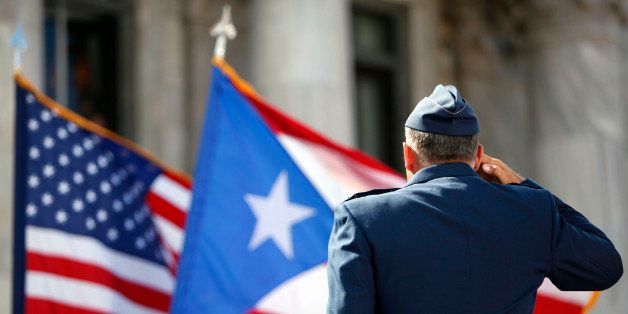 A member of the U.S. Army Honor Guard salutes the Puerto Rican and U.S. flags during the inaugural ceremony for governor-elect Alejandro Garcia Padilla, at the Capitol building in San Juan, Puerto Rico, Wednesday, Jan. 2, 2013. Garcia is a 41-year-old attorney and former local senator who narrowly defeated pro-statehood Gov. Luis Fortuno. He was sworn in on a stage overlooking the Atlantic Ocean amid the cheers of thousands of supporters from his party, which opposes statehood. (AP Photo/Ricardo Arduengo)