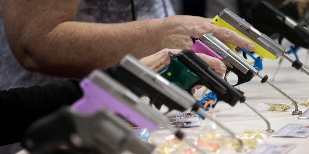 Attendees look over a pistol display at the National Rifle Association's annual convention in Friday, April 25, 2014 in Indianapolis. (AP Photo/AJ Mast)