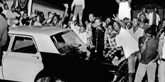 FILE - In this Aug. 12, 1965 file photo, demonstrators push against a police car after rioting erupted in the Watts district of Los Angeles. It began with a routine traffic stop 50 years ago this month, blossomed into a protest with the help of a rumor and escalated into the deadliest and most destructive riot Los Angeles had seen. The Watts riot broke out Aug. 11, 1965 and raged for most of a week. When the smoke cleared, 34 people were dead, more than a 1,000 were injured and some 600 buildings were damaged.(AP Photo, File)