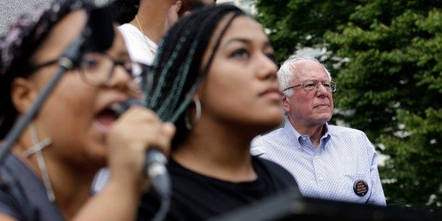 Marissa Johnson, left, speaks as Mara Jacqueline Willaford stands with her and Democratic presidential candidate Sen. Bernie Sanders, I-Vt., stands nearby as the two women take over the microphone at a rally Saturday, Aug. 8, 2015, in downtown Seattle. The women, co-founders of the Seattle chapter of Black Lives Matter, took over the microphone moments after Sanders began speaking and refused to relinquish it. Sanders eventually left the stage without speaking further and instead waded into the crowd to greet supporters. (AP Photo/Elaine Thompson)