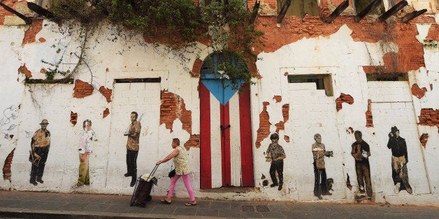 OLD SAN JUAN, PUERTO RICO - JULY 04: A woman walks by a rundown building on Saturday July 04, 2015 in Old San Juan, Puerto Ri