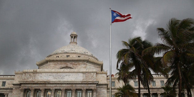 SAN JUAN, PUERTO RICO - JULY 01: The Puerto Rican flag flies near the Capitol building as the island's residents deal with the government's $72 billion debt on July 1, 2015 in San Juan, Puerto Rico. Governor of Puerto Rico Alejandro GarcÃa Padilla said in a speech recently that the people of Puerto Rico will have to make sacrifices and share the responsibilities to help pull the island out of debt. (Photo by Joe Raedle/Getty Images)