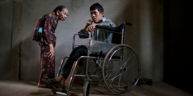 CAM LO, VIETNAM -MARCH 8: Le Van Khanh,38 (left) stands next to his mother Nguyen Thi Huyen March 8, in Cam Lo, in Quang Tri province, Vietnam. Le Van was born deaf, mentally handicapped with legs that are deformed, he is wheelchair bound most of the time and his elderly mother can't physically handle the responsibility of her handicapped son.Nguyen lost 2 children in addition as well and gets a small stipend from the government. Many of the families have had little access to medical care and don't even understand the medical term for the disability that their children have since birth. They only know that the defoliant used by the US military during the Vietnam war called Agent orange caused this. More than 30 years after the war in Vietnam, a battle is still being fought to help people suffering from the effects of Agent Orange. Between 1961 and 1971, the U.S military sprayed nearly 20 million gallons of Agent Orange and other herbicides across Vietnam in an attempt to kill vegetation that hid the enemy. Much of it contained the toxic nerve gas called dioxin. After so many years has past, studies have stated that lingering health and environmental problems effected an estimated 3 million Vietnamese, including 150,000 children. As a result an increased number of Vietnamese children have been born with severe birth defects and Down syndrome since the war ended in 1975. Recently, Vietnamese and U.S policymakers have finally started the first phase to clean up environmental damage leftover from the chemical defoliant. The action plan urges the U.S government to provide an estimated $30 million annually over 10 years to clean up sites still contaminated by dioxin. (Photo by Paula Bronstein /Getty Images)