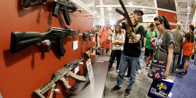 In this photo taken with a wide angle lens, people examine rifles on display during the annual National Rifle Association convention Saturday, April 11, 2015, in Nashville, Tenn. (AP Photo/Mark Humphrey)