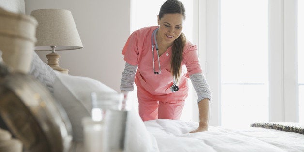 Home nurse making patients bed
