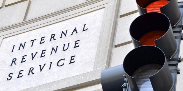 Internal Revenue Service sign with a traffic signal in the foreground indicating a red light.