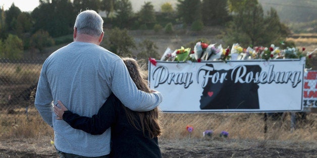 ROSEBURG, OR - OCTOBER 03: Dave (L) and Robin Griffiths leave flowers at a memorial along the road to Umpqua Community Colle