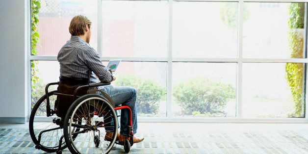 Businessman in wheelchair using digital tablet in office