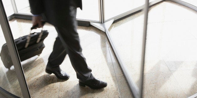 Businessman with suitcase using revolving door