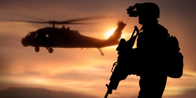 Combat ready special operation forces soldier in an Afghanistan war scene with a black hawk helicopter.