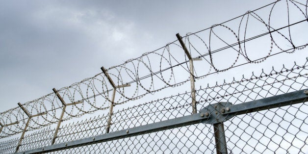 wired fence with barbed wires on blue sky background 