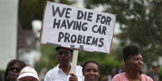 WEST PALM BEACH, FL - OCTOBER 28: Justin Hepburn holds a sign reading, 'We die for having car problems' as he attends a rally for Corey Jones in front of the State Attorney's office asking that the process of justice be transparent after the 31 year old was shot and killed by a plainclothes police officer on October 28, 2015 in West Palm Beach, Florida. The family of the church drummer is seeking answers to why he was shot dead as he waited at his disabled car by a Palm Beach Gardens Police department plainclothes police officer on October 18th. (Photo by Joe Raedle/Getty Images)