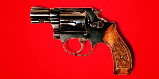 Hand gun against red background, close-up