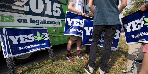 College students collect lawn signs at a promotional tour bus from ResponsibleOhio, a pro-marijuana legalization group, at Miami University, Friday, Oct. 23, 2015, in Oxford, Ohio. A ballot proposal before Ohio voters this fall would be the first in the Midwest to take marijuana use and sales from illegal to legal for both personal and medical use in a single vote. (AP Photo/John Minchillo)