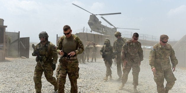 TO GO WITH AFGHANISTAN-US-ARMY-CONFLICT-FOCUS BY GUILLAUME DECAMMEIn this photograph taken on August 13, 2015, US army soldiers walk as a NATO helicopter flies overhead at coalition force Forward Operating Base (FOB) Connelly in the Khogyani district in the eastern province of Nangarhar. From his watchtower in insurgency-wracked eastern Afghanistan, US army Specialist Josh Whitten doesn't have much to say about his Afghan colleagues. 'They don't come up here anymore, because they used to mess around with our stuff. 'Welcome to Forward Operating Base Connelly, where US troops are providing training and tactical advice to the 201st Afghan army corps as they take on the Taliban on the battlefield. AFP PHOTO / Wakil Kohsar (Photo credit should read WAKIL KOHSAR/AFP/Getty Images)