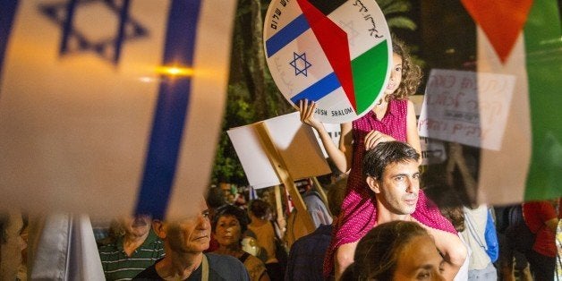 A young girl holds a bearing images of the Israeli and Palestinian flags during a Israeli left-wing activist rally demanding