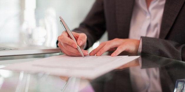 Businesswoman writing on paper at desk