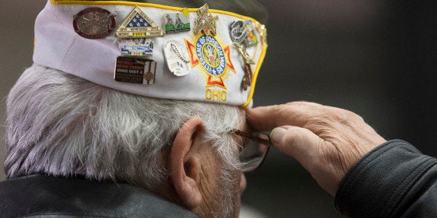 Retired USMC Maj. William Fry salutes during the pledge of allegiance during a Veterans Day ceremony in the Countryside YMCA's gymnasium, Wednesday, Nov. 11, 2015, in Lebanon, Ohio. The Maineville, Ohio veteran served for 21 years. (AP Photo/John Minchillo)