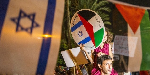 A young girl holds a bearing images of the Israeli and Palestinian flags during a Israeli left-wing activist rally demanding fresh Israeli-Palestinian peace talks, on the eve of the 20th anniversary of the killing of late Israeli prime minister Yitzhak Rabin, at the Rabin Square in the Israeli city of Tel Aviv on October 24, 2015. Activist group Peace Now -- which organised the rally along with the left-wing Meretz party and others -- estimated there were some 6,000 people attending the protest at Rabin Square, the site where the Nobel peace laureate was gunned down by a right-wing Jewish extremist at the age of 73 on November 4, 1995. AFP PHOTO / JACK GUEZ (Photo credit should read JACK GUEZ/AFP/Getty Images)