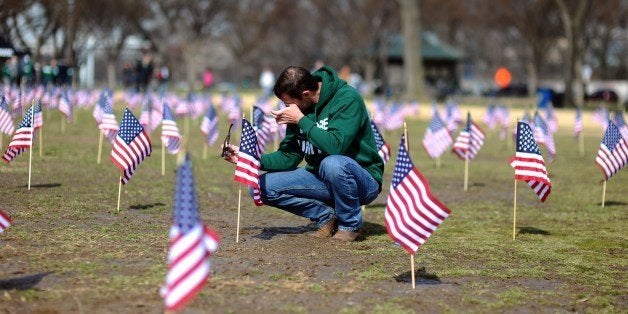 US Navy Iraq war veteran Jeff Hensley wipes his tears as he helps set up 1,892 American flags on the National Mall in Washington, DC, on March 27, 2014. The Iraq and Afghanistan Veterans installed the flags to represent the 1,892 veterans and service members who committed suicide this year as part of the 'We've Got Your Back: IAVA's Campaign to Combat Suicide.' AFP PHOTO/Jewel Samad (Photo credit should read JEWEL SAMAD/AFP/Getty Images)