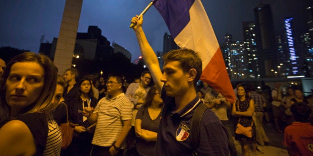 A man carries French national flag as people gather in Hong Kong, Saturday, Nov. 14, 2015, to mourn for the victims killed in
