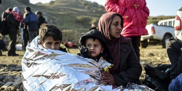 A Syrian family waits after arriving on the Greek island of Lesbos along with other migrants and refugees, on November 17, 2015, after crossing the Aegean Sea from Turkey. At least eight people drowned when a boat carrying migrants from Turkey sank off the Greek island of Kos, the coastguard said on November 17, 2015. They were the latest of nearly 3,500 deaths at sea this year among people making desperate bids to flee war and poverty and to reach Europe, according to UN figures. European leaders tried to focus on joint action with Africa to tackle the migration crisis, as Slovenia became the latest EU member to act on its own by barricading its border. AFP PHOTO/BULENT KILIC (Photo credit should read BULENT KILIC/AFP/Getty Images)