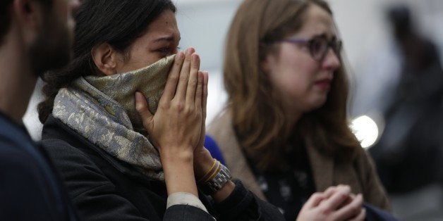 People spend a moment mourning the dead at the site of the attack at the Cafe Belle Equipe on rue de Charonne, prior to going to work early on November 16, 2015 in Paris, three days after the terrorist attacks that left over 130 dead and more than 350 injured. France prepared to fall silent at noon on November 16 to mourn victims of the Paris attacks after its warplanes pounded the Syrian stronghold of Islamic State, the jihadist group that has claimed responsibility for the slaughter. AFP PHOTO / KENZO TRIBOUILLARD (Photo credit should read KENZO TRIBOUILLARD/AFP/Getty Images)