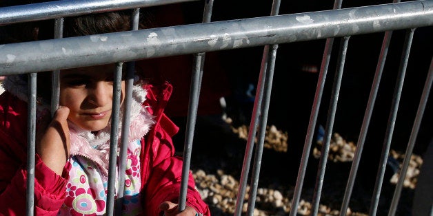 A migrant girl looks through the fence waiting to register with the police, in a refugee center in the southern Serbian town of Presevo, Tuesday, Nov. 17, 2015. Europe faces a massive refugee crisis. More than 600,000 people have made their way through Greece, Macedonia and Serbia so far this year, fleeing war and poverty at home. (AP Photo/Darko Vojinovic)