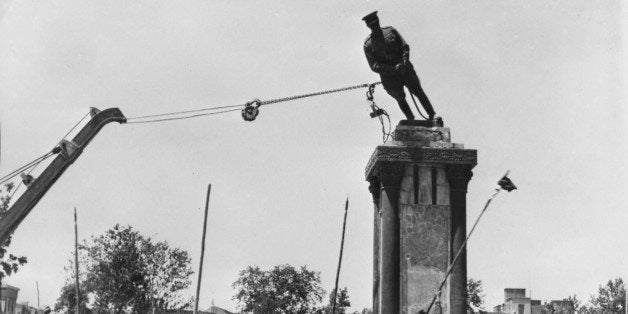 A crowd of Persian Prime Minister Mohammed Mossadegh supporters, armed with long sticks tear down a statue of Shah Reza, fath