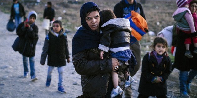 A woman carries a child as migrants and refugees walk near Gevgelija, after crossing the Greece-Macedonia border, on November