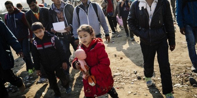 A girl carries her doll as she along with other migrants and refugees walk after crossing the Greek-Macedonian border near Ge