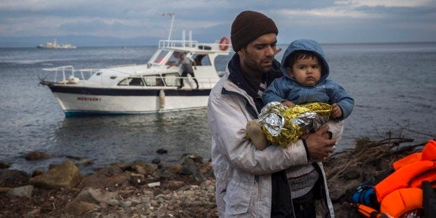 A father holds his baby after their arrival on a vessel with other refugees and migrants from the Turkish coast to the northe