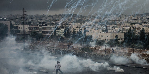 JERUSALEM, Nov. 6, 2015 -- Palestinian protesters evade from a shower of tear gas cylinders shot by Israeli security forces during clashes in the West Bank city of Bethlehem, on Nov. 6, 2015. Clashes between Palestinian protesters and Israeli security forces broke out in Bethlehem on Friday, with Palestinians setting roadblocks, lighting tyres and hurling stones toward Israeli security forces and Israeli security forces firing tear gas cylinders to disperse Palestinian protesters. The current wave of tension in the Palestinian territories and the clashes with the Israeli security forces killed so far 75 Palestinians and wounded more than 2,000 others that has been going on since Oct. 1. Eleven Israelis were killed in the meantime in a series of shooting, stabbing and cars running over attacks in the West Bank, east Jerusalem and Israel. (Xinhua/Li Rui via Getty Images)