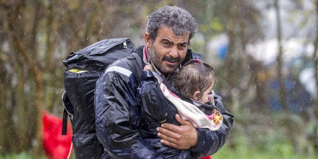 A migrant carries his child after crossing the Greek-Macedonian border, near Gevgelija, on November 27, 2015.Since last week, Macedonia has restricted passage to northern Europe to only Syrians, Iraqis and Afghans who are considered war refugees. All other nationalities are deemed economic migrants and told to turn back. Some 800 people are stuck on the border, mostly Iranians, Moroccans, Bangladeshis and Pakistanis. AFP PHOTO / ROBERT ATANASOVSKI / AFP / ROBERT ATANASOVSKI (Photo credit should read ROBERT ATANASOVSKI/AFP/Getty Images)