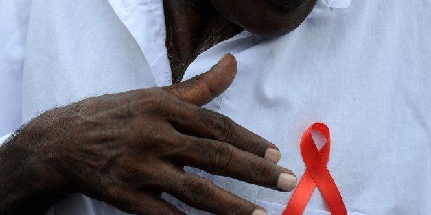 A Sri Lankan prisoner gestures towards a red ribbon on his chest as he takes part in a gathering to mark World AIDS Day at a prison complex in Colombo on December 5, 2015. AFP PHOTO / LAKRUWAN WANNIARACHCHI / AFP / LAKRUWAN WANNIARACHCHI (Photo credit should read LAKRUWAN WANNIARACHCHI/AFP/Getty Images)