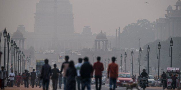 Indian pedestrians walk near smog enveloped government offices on Rajpath in New Delhi on December 1, 2015. India's capital, with 18 million residents, has the world's most polluted air with six times the amount of small particulate matter (pm2.5) than what is considered safe, according to the World Health Organization (WHO). The air's hazardous amount of pm2.5 can reach deep into the lungs and enter the blood, causing serious long term health effect, with the WHO warning India has the world's highest death rate from chronic respiratory diseases. India, home to 13 of the world's top 20 polluted cities, is also the third largest emitter of greenhouse gases behind the United States and China. Rich countries should not force the developing world to abandon fossil fuels completely, Indian Prime Minister Narendra Modi said at the UN climate summit in Paris on December 1. Almost a third of India's population remains in severe poverty with limited access to electricity, and its government sees little chance of boosting their prospects without turning to cheap and plentiful coal. AFP PHOTO / ROBERTO SCHMIDT / AFP / ROBERTO SCHMIDT (Photo credit should read ROBERTO SCHMIDT/AFP/Getty Images)